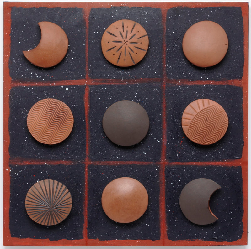Round textured terra cotta and black ceramic pods on a blue grid background sprinkled with white and yellow accents to resemble outer space