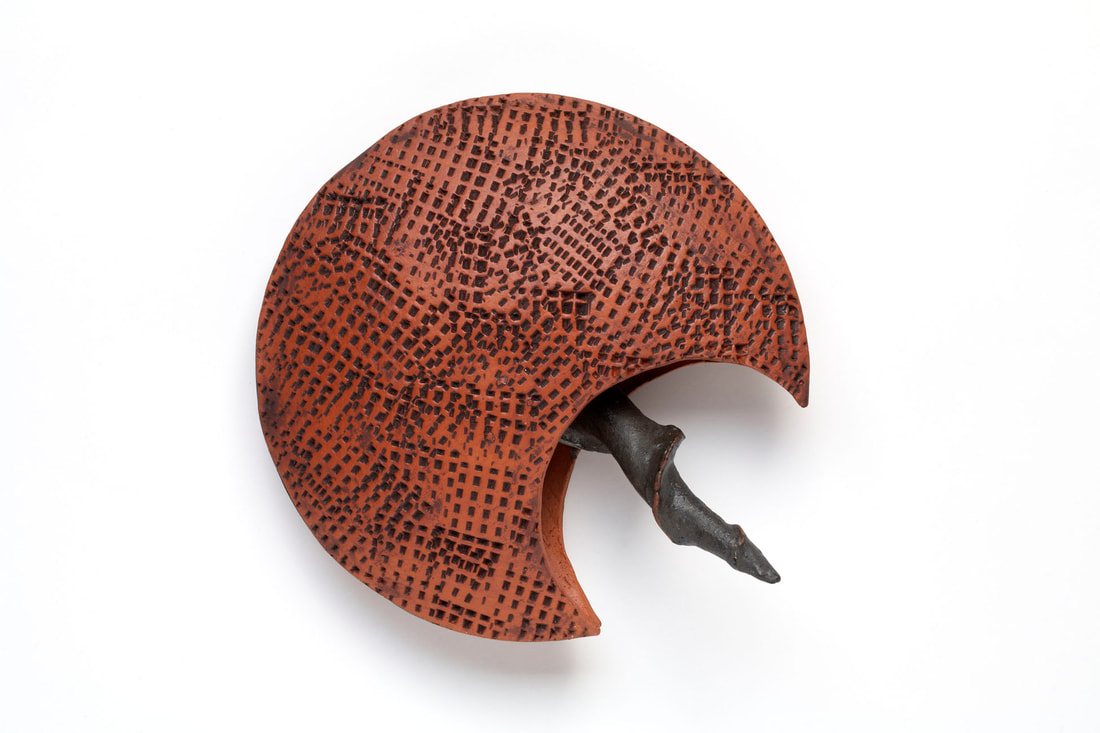  Abstract textured terra cotta wall sculpture with black accent resembling a tailed  aquatic creature like a  horseshoe crab